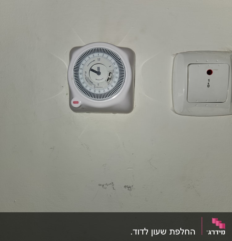 שעון טיימר חשמלי ומתג על קיר לבן